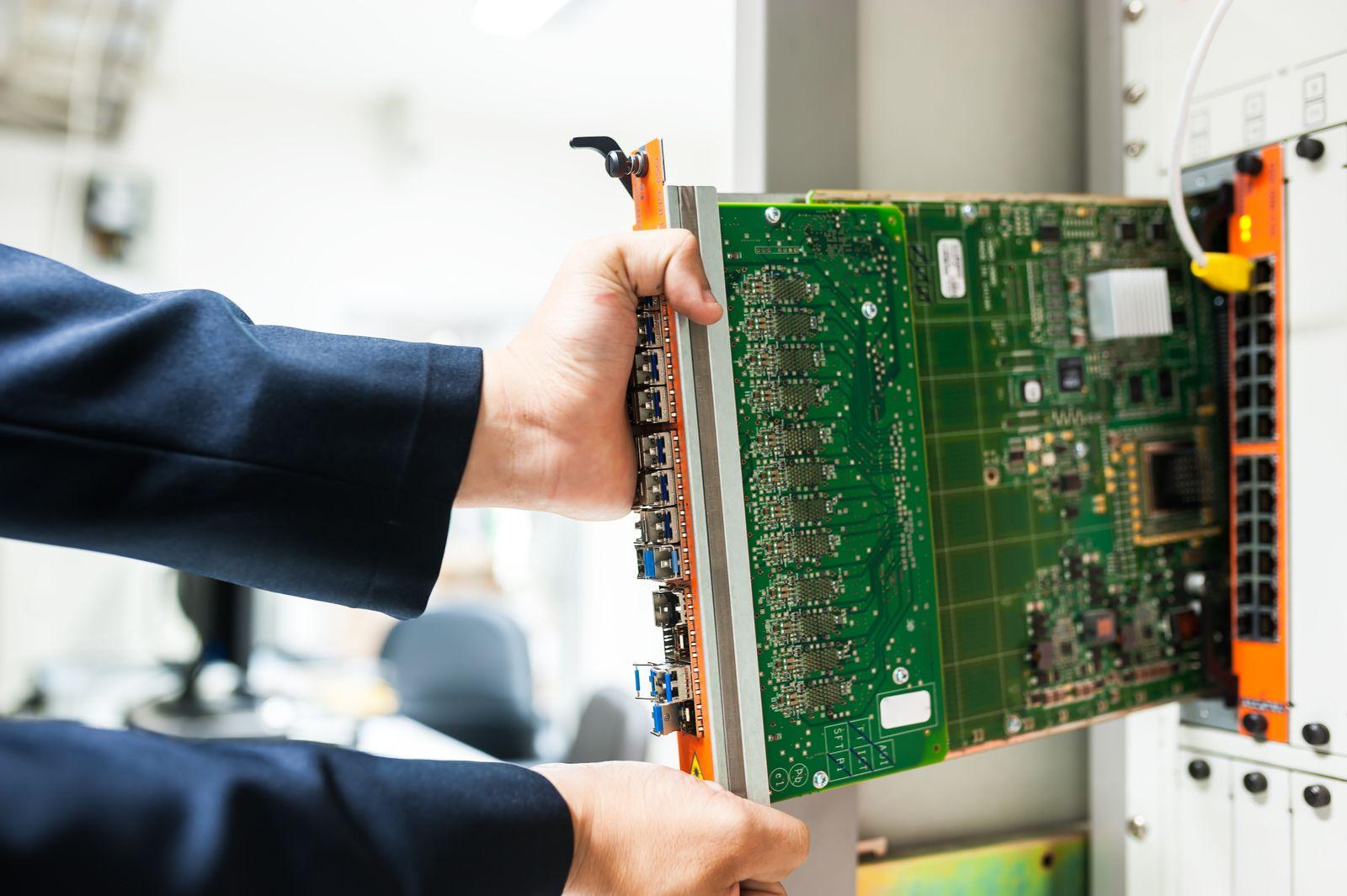 A technician installing a circuit board into a server rack
